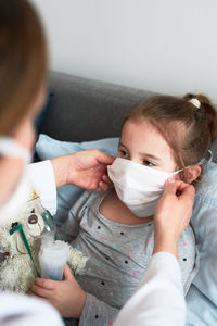 High angle view of woman wearing mask to daughter