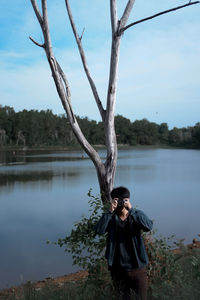 Man photographing while standing by lake