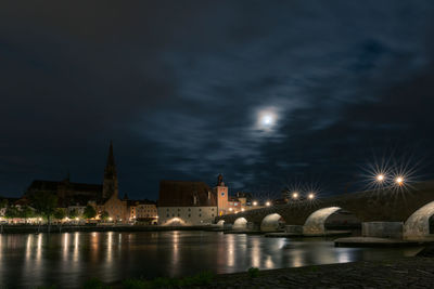 Illuminated buildings by river at night