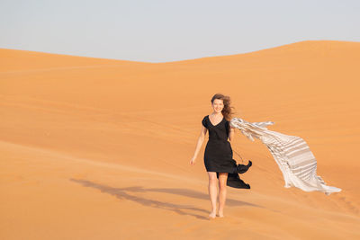 Full length of woman on sand dune in desert