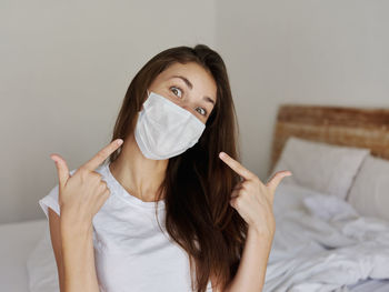 Portrait of beautiful woman with hand on bed at home