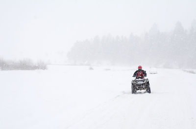 Man driving quadbike on snow covered field
