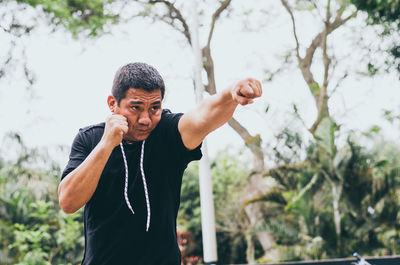 Young man standing against trees