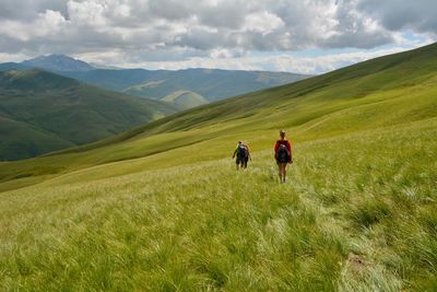 Rear view of people walking on mountain against sky