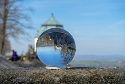 Close-up of crystal ball on rock by building against sky