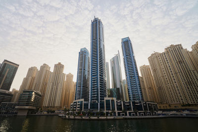 Low angle view of skyscrapers against cloudy sky