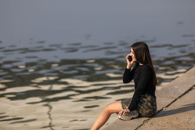 A lovely beautiful teenager talking on her mobile phone.copy space on the defocussed lake behind her