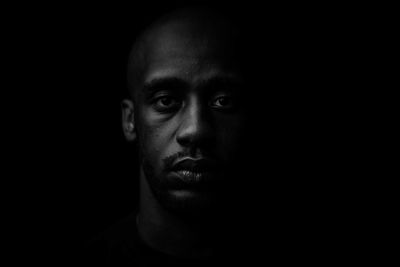 Close-up portrait of young man against black background