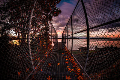 Illuminated chainlink fence against sky during sunset