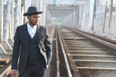 Man in suit looking away while standing at railway bridge