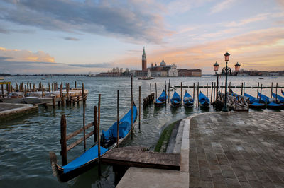 Gondolas moored at grand canal by santa maria della salute against sky