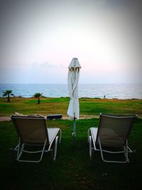 Rear view of chairs on beach against sky