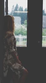 Rear view of woman looking through window