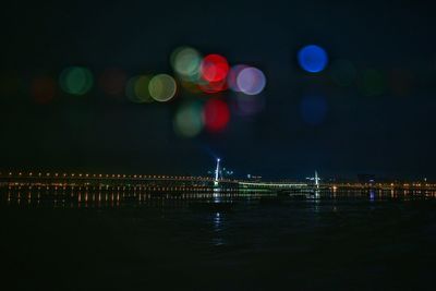 Mid distance of illuminated lighthouse by sea at night