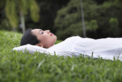 Woman lying on grassy field at park