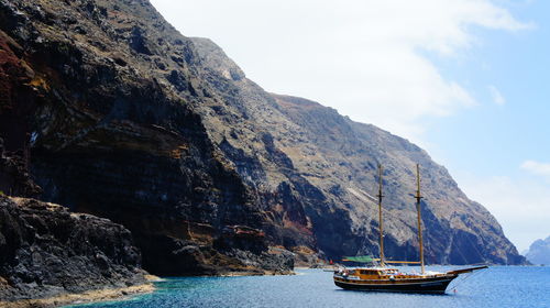 Boats in sea with mountains in background