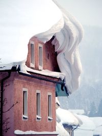 Low angle view of icicles on snow covered building against sky
