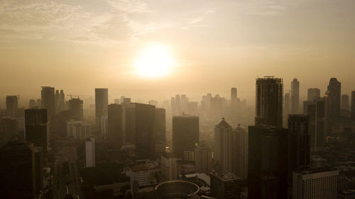 Modern buildings in city against sky during sunset