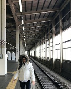 Woman wearing fur hood standing at railroad station platform