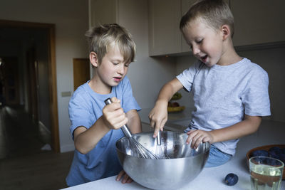 Brothers mixing cake batter in kitchen at home