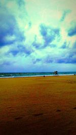 View of calm beach against cloudy sky