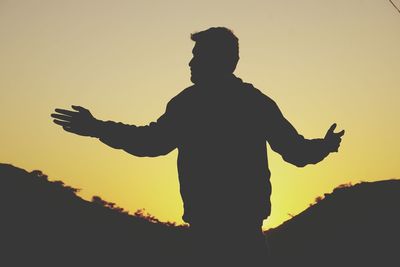 Rear view of silhouette man standing against sky during sunset