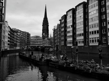 Bridge over river amidst buildings in city against sky