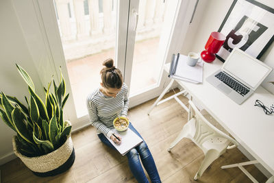 Woman sitting on floor writing on notepad