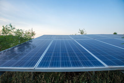 Solar panels on land against sky during sunset