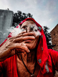 Portrait of woman in red clothes sitting outdoors while smoking