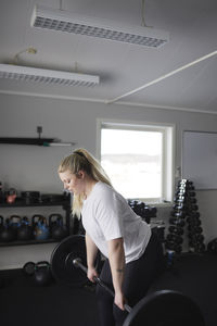 Mid adult woman lifting barbell in gym