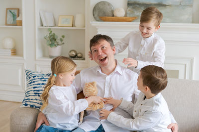 An annoyed father sitting on sofa at home in living room distracted from noise