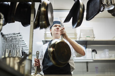 Low angle view of chef arranging frying pan in commercial kitchen