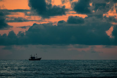 Boat sailing in sea against sky during sunset.