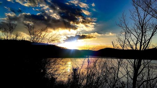 Silhouette trees by lake against sky during sunset