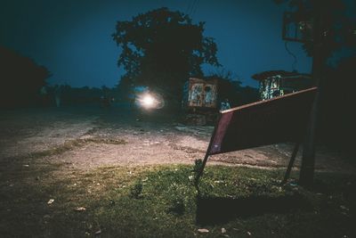 Illuminated street light by trees at night