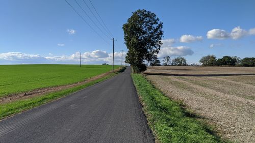 Road amidst field against sky