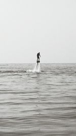 Silhouette of man flyboarding at sea
