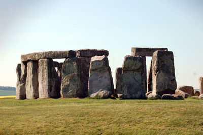 Stonehenge on grassy field against clear sky