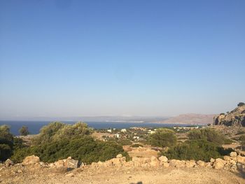 Scenic view of landscape and sea against clear blue sky