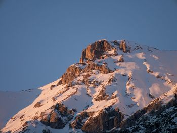 Low angle view of snowcapped mountain against clear blue sky