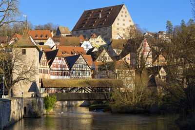 Bridge over river by buildings against sky