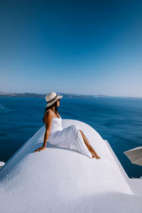 Woman in hat against sea against clear blue sky