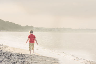 Rear view of boy walking along shore