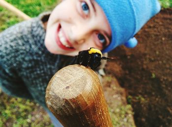 Portrait of smiling girl looking at bee on wood