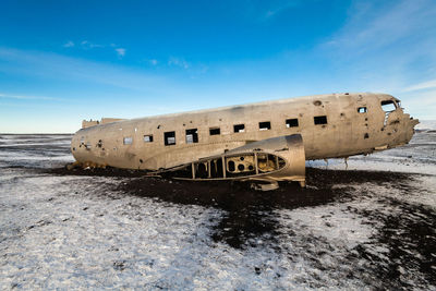 Abandoned boat on beach against sky during winter