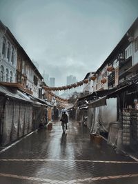 People walking on wet city street against sky