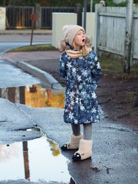 Full length of cute girl standing against wall