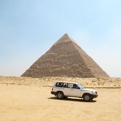 Vintage car on desert land against clear sky