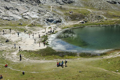 People at lakeshore against mountains